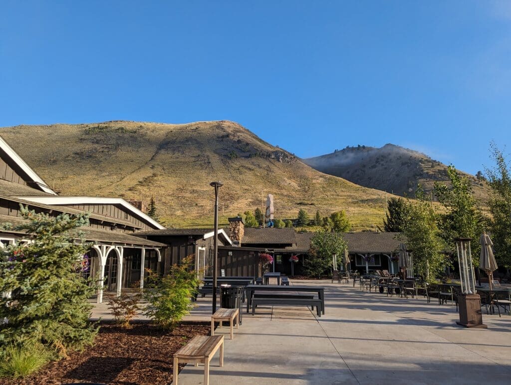 a building with benches and trees in front of a mountain