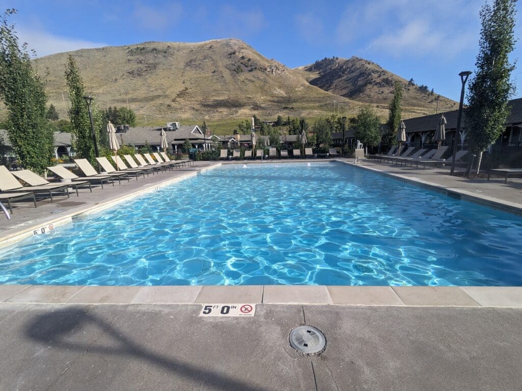 a pool with chairs and a mountain in the background