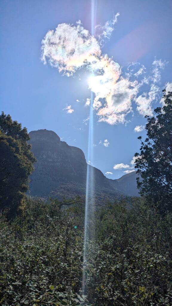 sun shining through the clouds over a mountain