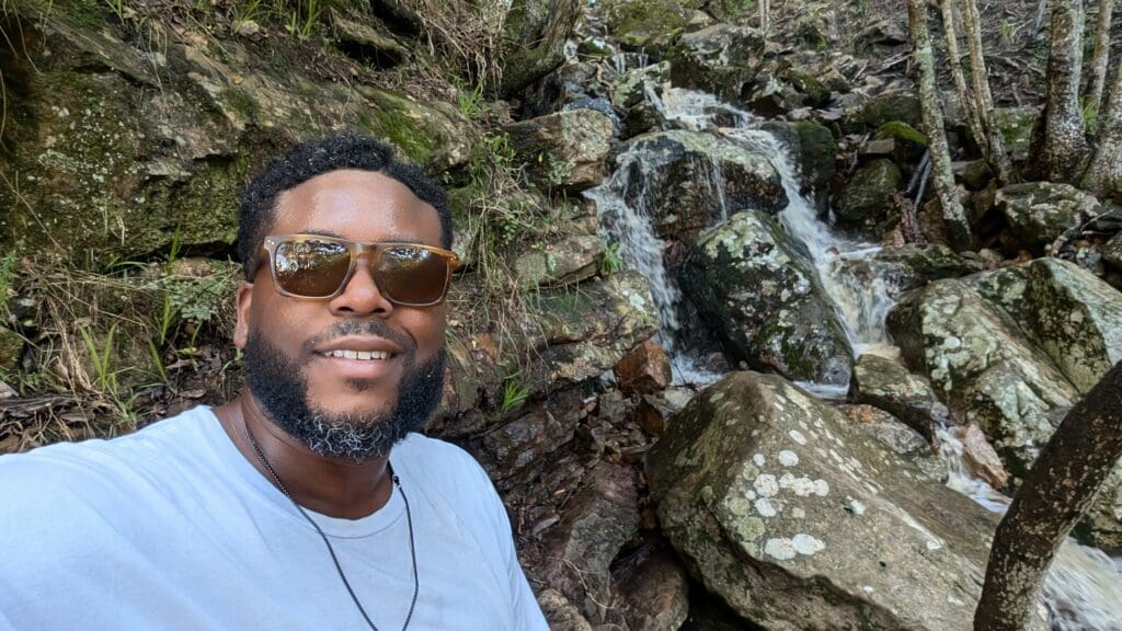 a man taking a selfie in front of rocks and water