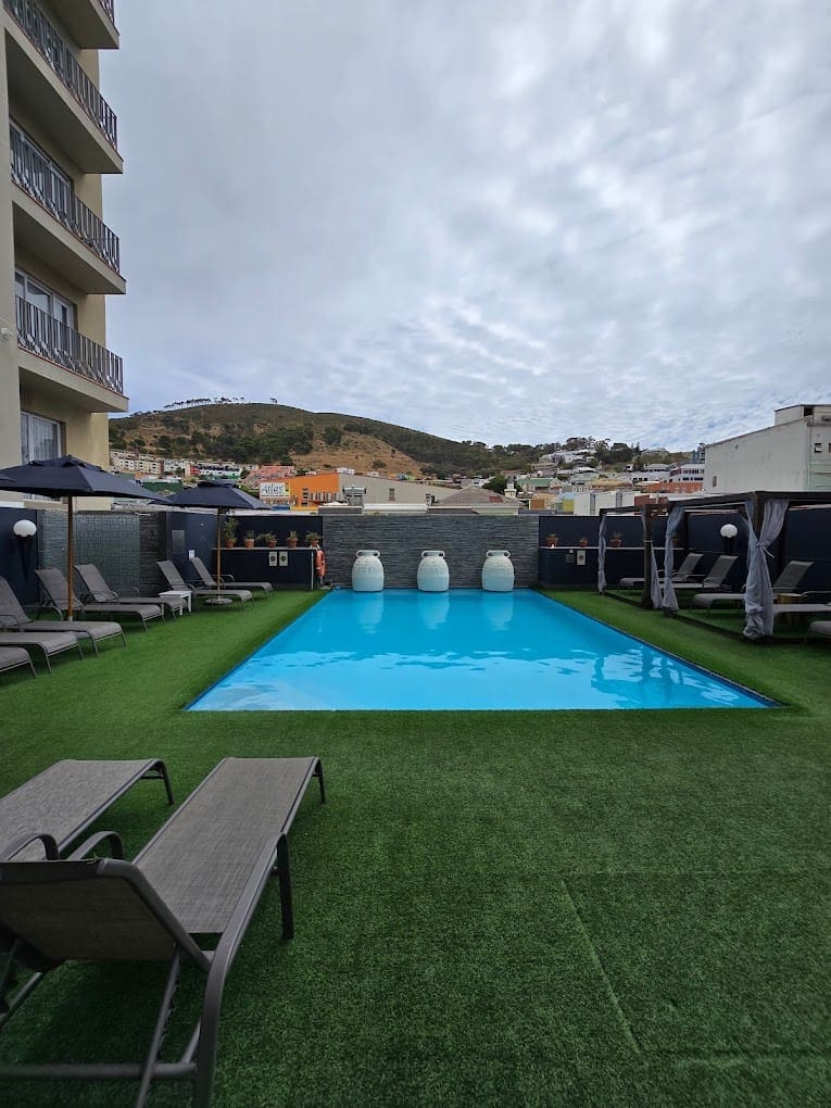 a pool with chairs and umbrellas on a rooftop