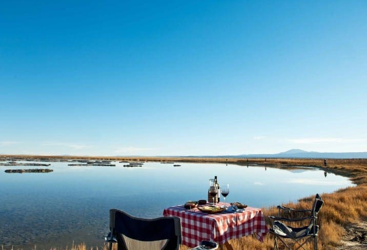 a picnic table with wine and chairs on a lake