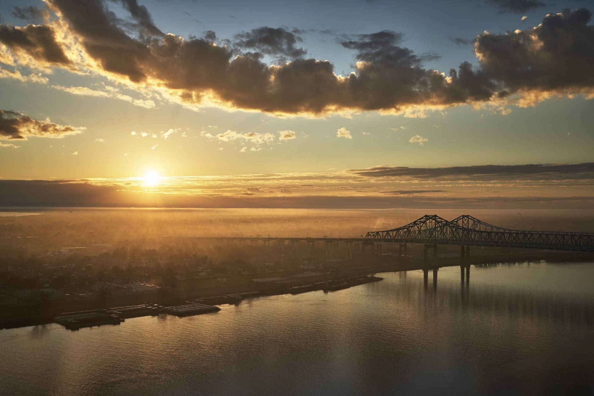 a bridge over water with a city and clouds in the sky
