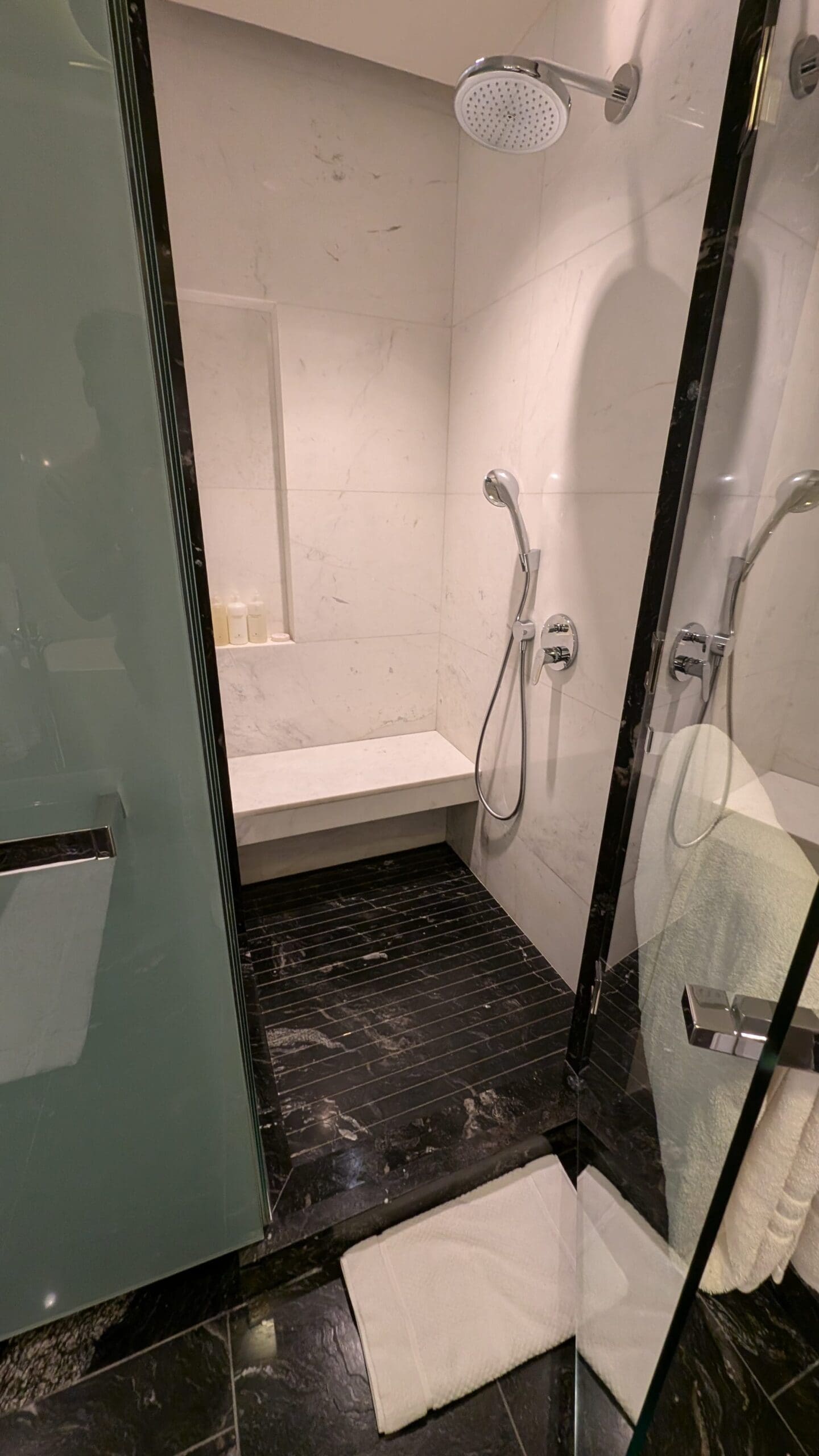 a shower with a bench and a white towel