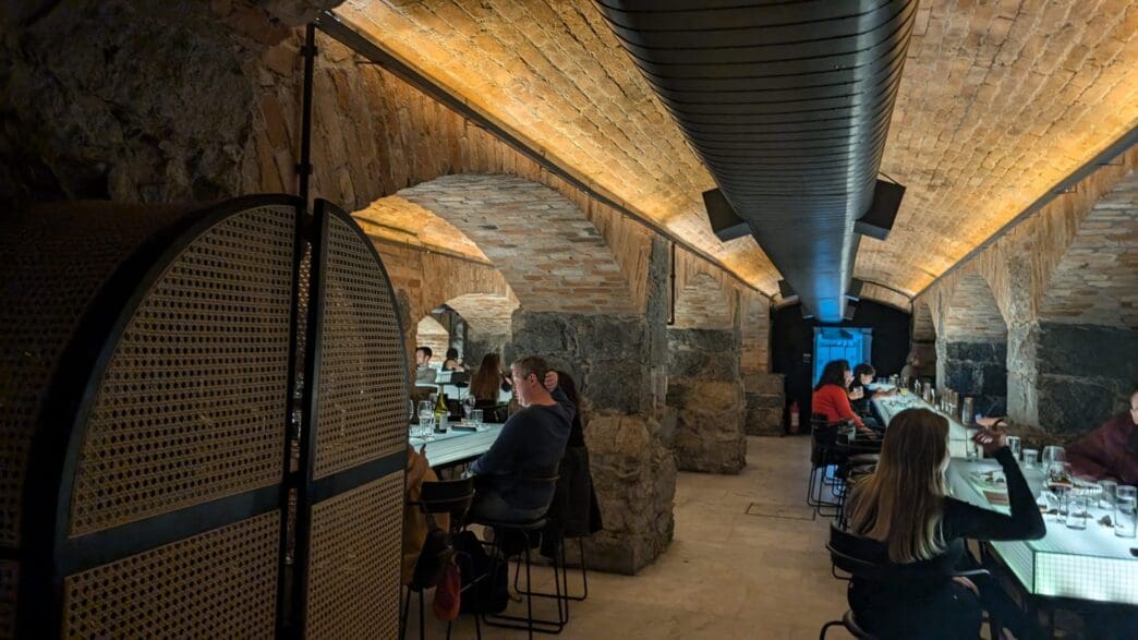 people sitting at tables in a room with brick walls and a brick ceiling