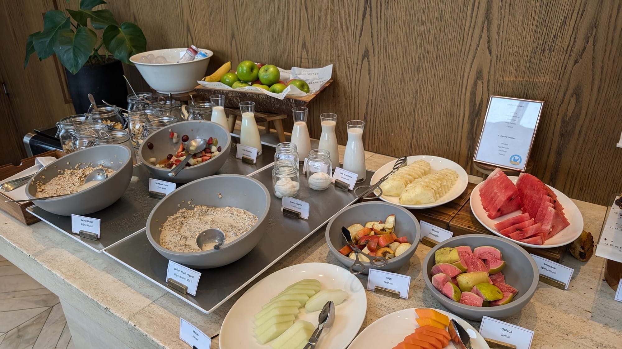 a buffet table with bowls of fruit and milk