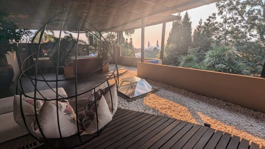 a patio with a swing chair and a glass table