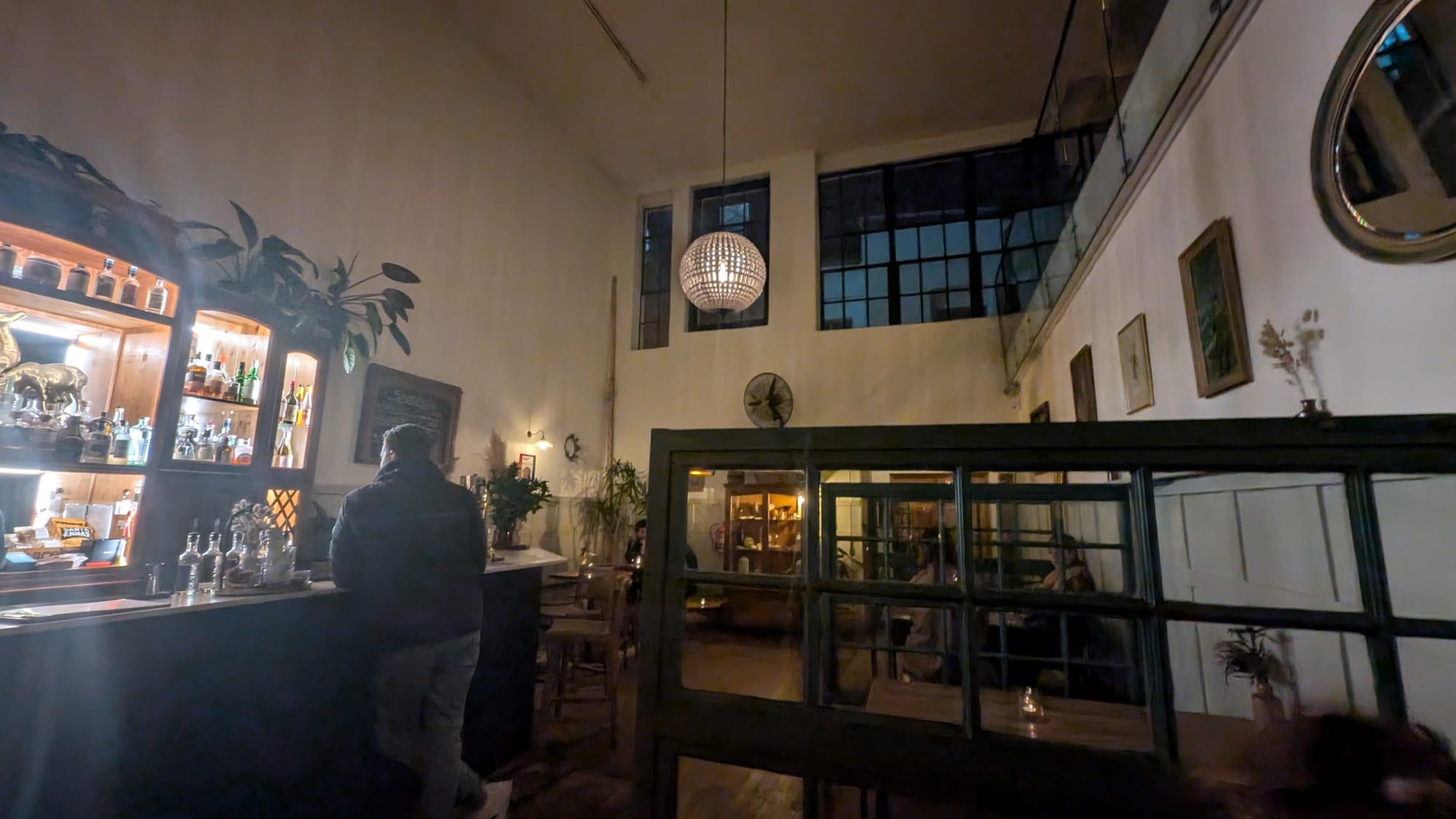 a man standing in a room with a glass wall and a chandelier
