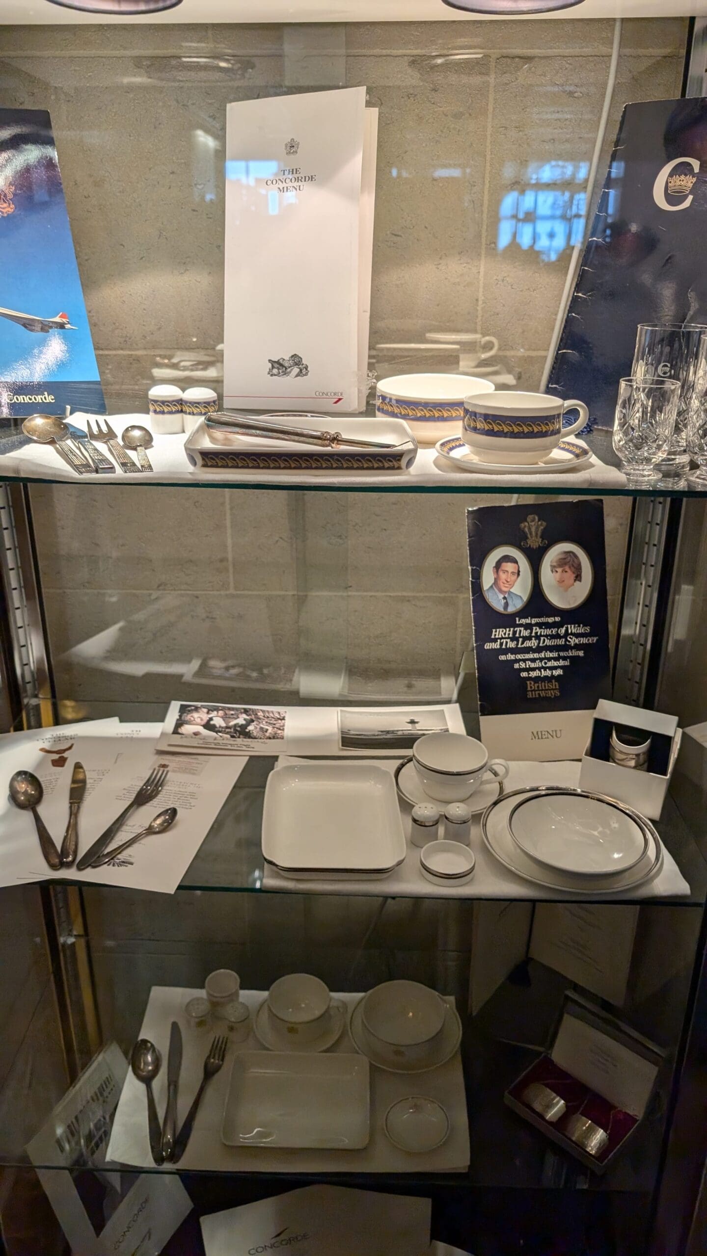 a glass cabinet with a glass shelf with silverware and plates