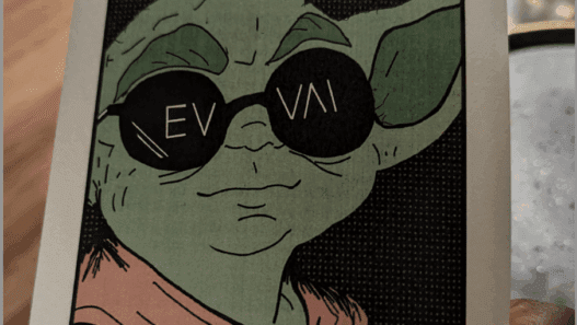 a hand holding a card with a cartoon character wearing sunglasses