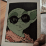 a hand holding a card with a cartoon character wearing sunglasses