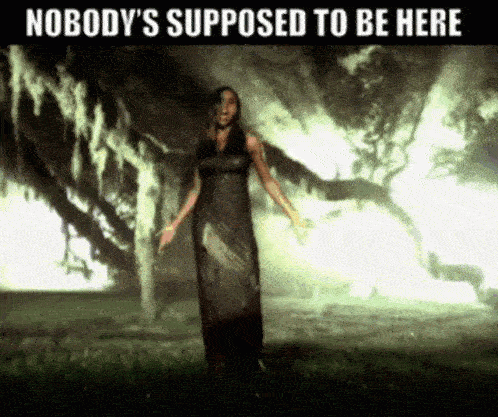 a woman in a long dress standing in front of a tree