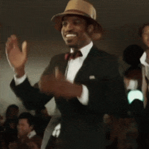 a man in a suit and hat waving