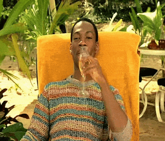 a man sitting in a chair drinking from a glass