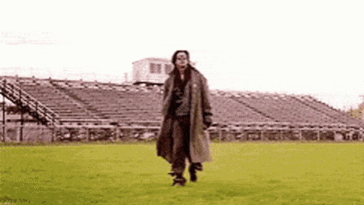 a man in a long coat running on grass
