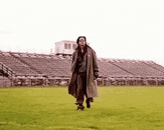a man in a long coat running on grass