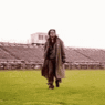 a man in a long coat running on grass
