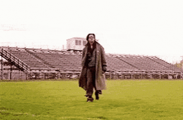 a man in a long coat running on grass