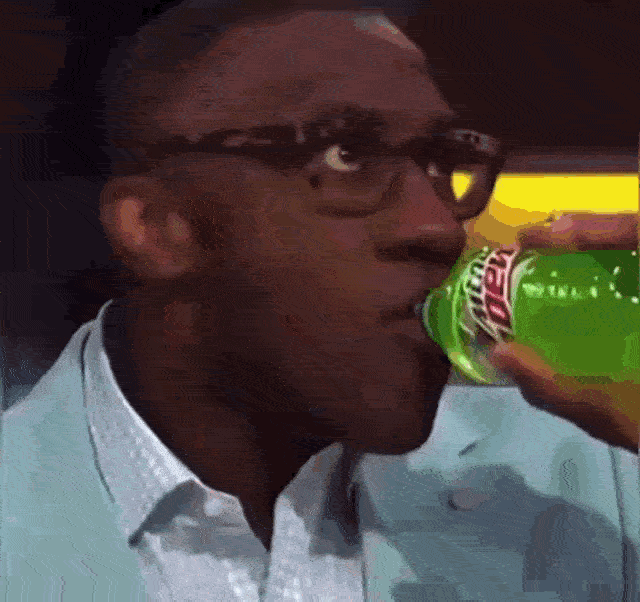 a man drinking a green soda
