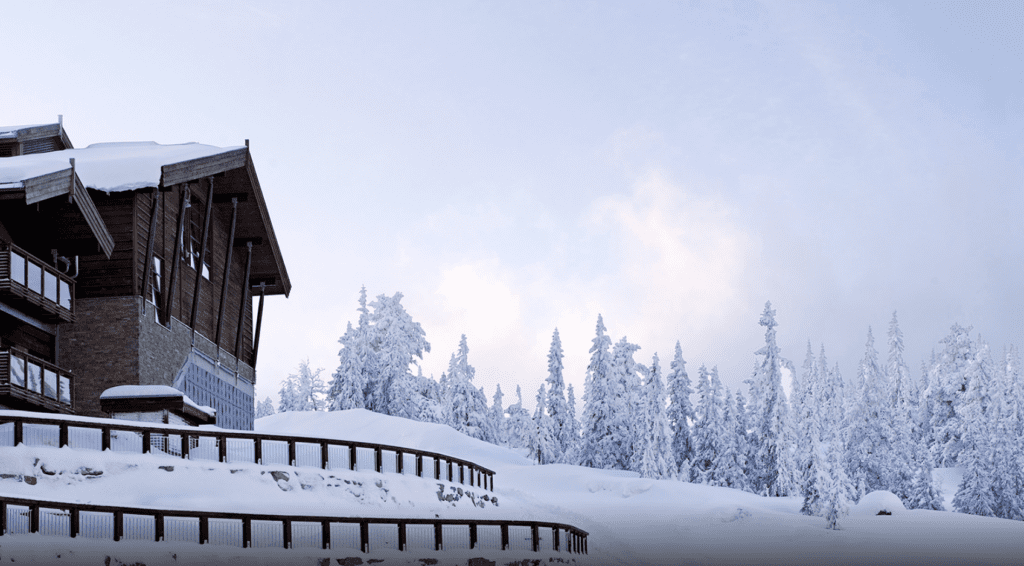 a building with a fence and snow covered trees