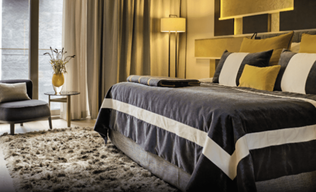 a bed with a rug and a vase of flowers