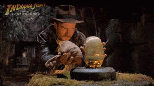a man in a hat and gloves looking at a gold object