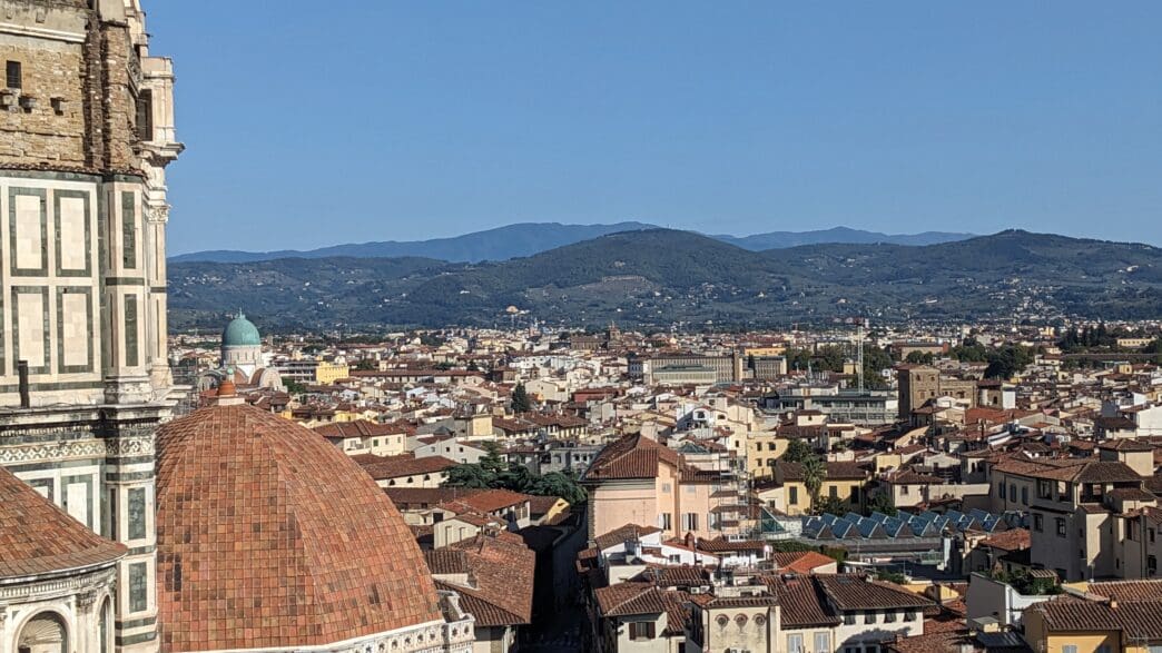 a city with a tower and a hill in the background
