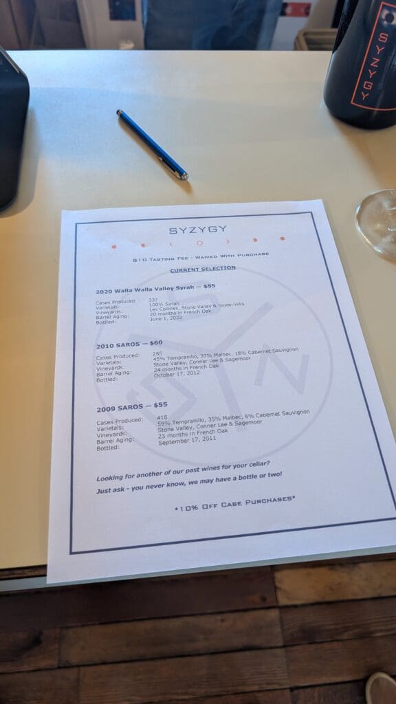 a paper with a pen and a glass on a table