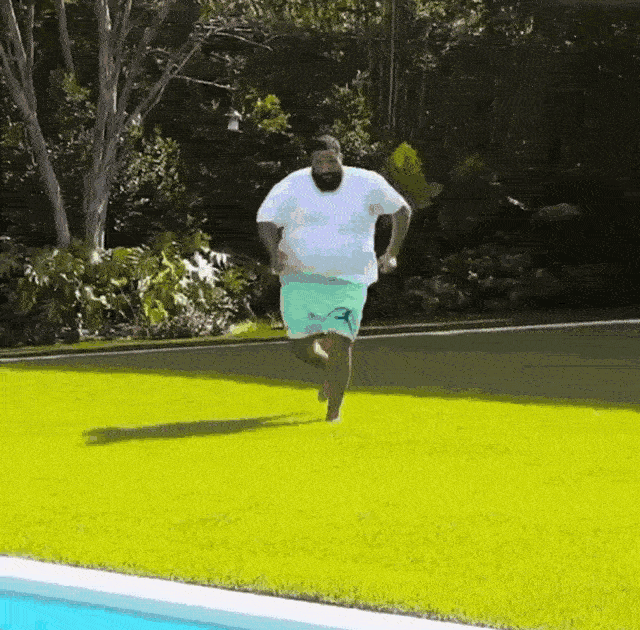 a man running on grass by a pool