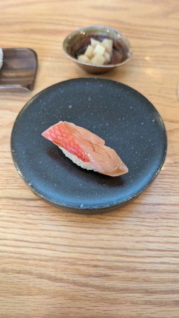 a piece of sushi on a black plate