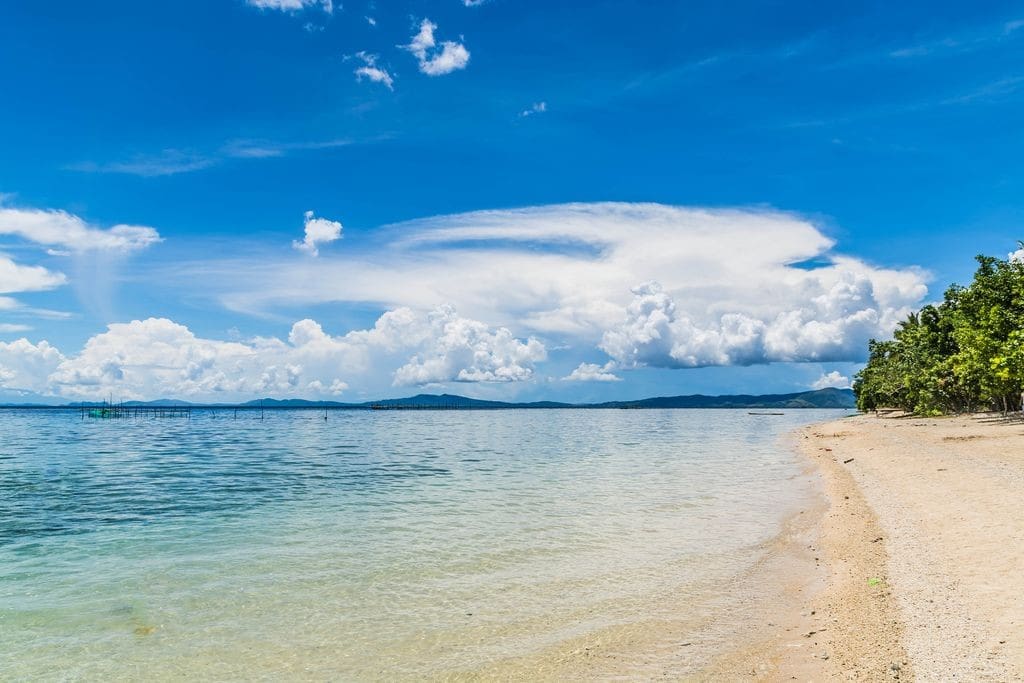 a beach with a body of water and a blue sky