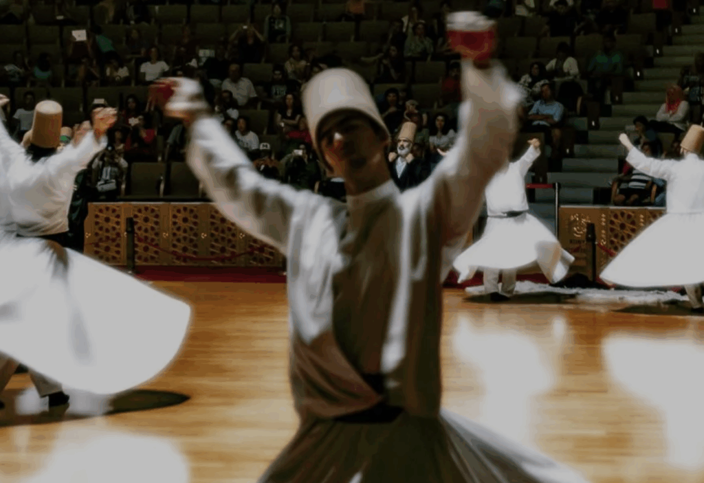 a man in a white robe dancing with a crowd of people in the background