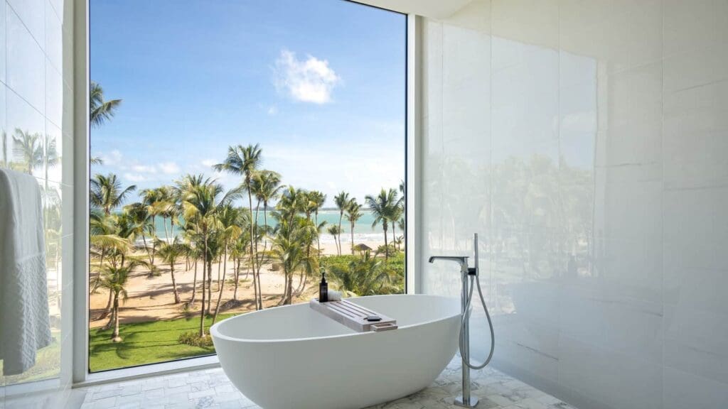 a bathtub in a bathroom with a large window overlooking a beach