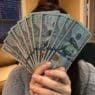 a person holding a fan of money