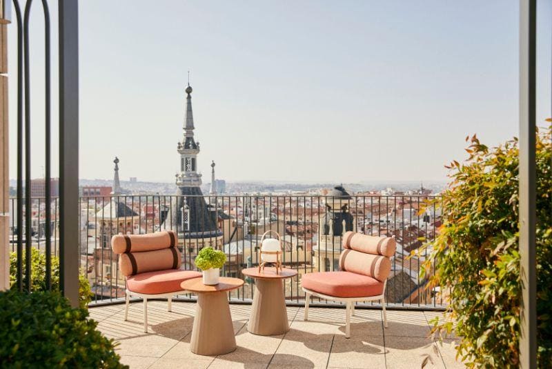 chairs and a table on a balcony overlooking a city