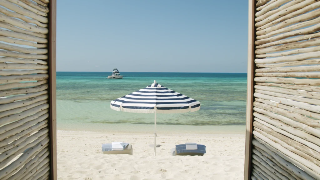 a beach with umbrella and chairs on the sand