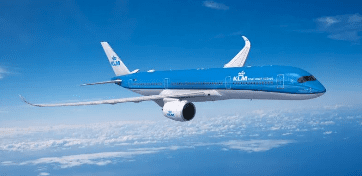 a blue and white airplane flying above clouds
