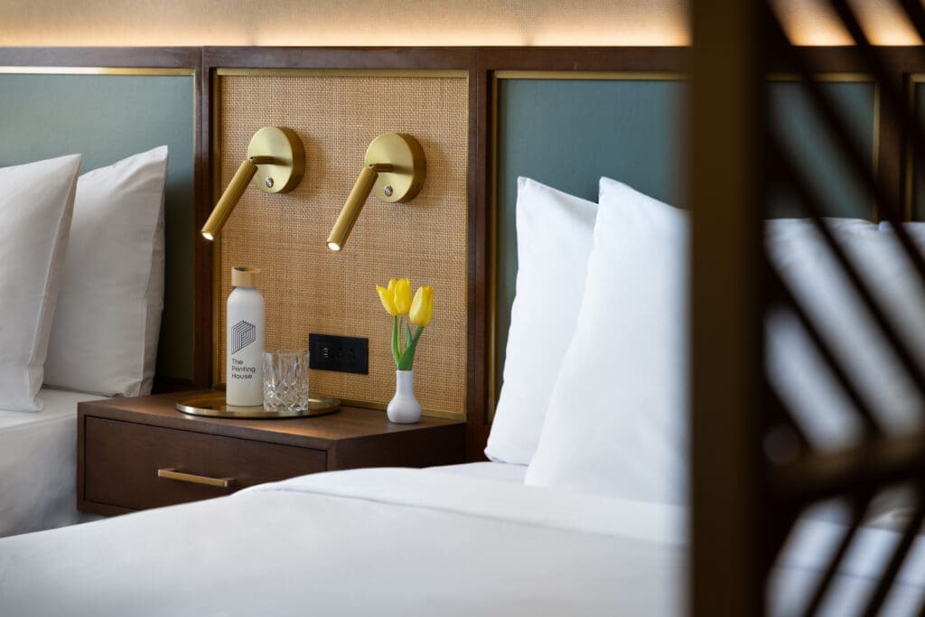 a bed with white pillows and a vase of flowers
