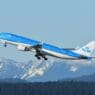 a blue and white airplane flying over mountains