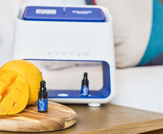 a small bottle of essential oil next to a fruit