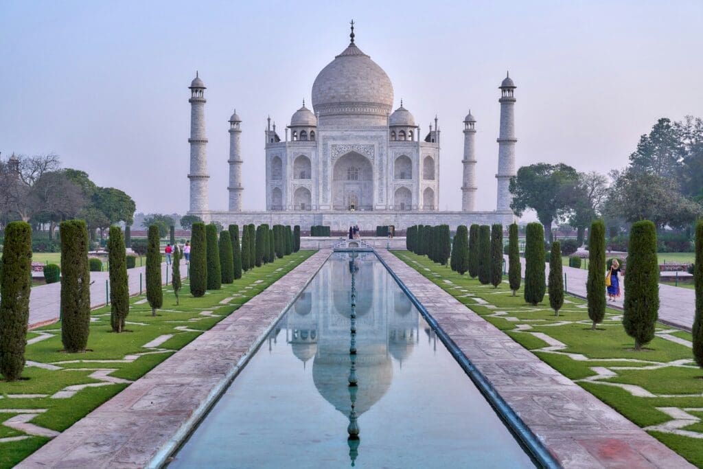 a large white building with a pool of water with Taj Mahal in the background