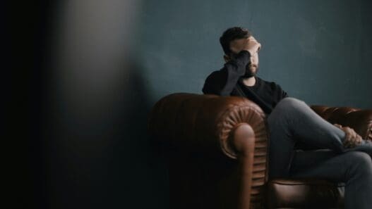 a man sitting on a couch with his hand on his face