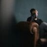 a man sitting on a couch with his hand on his face