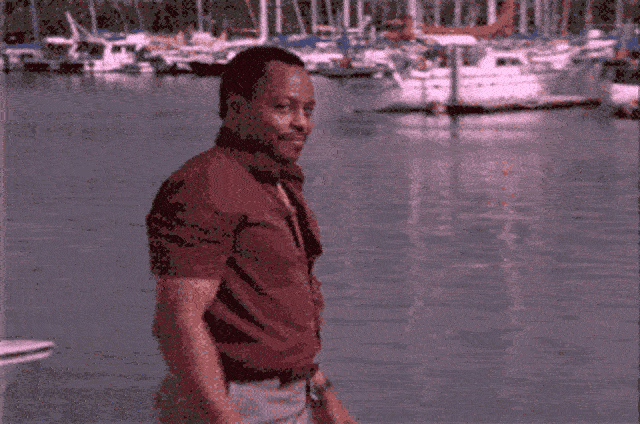 a man standing in water with boats in the background