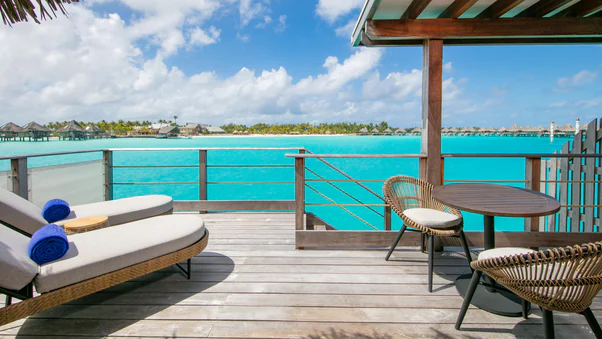 a deck with chairs and a table overlooking the ocean