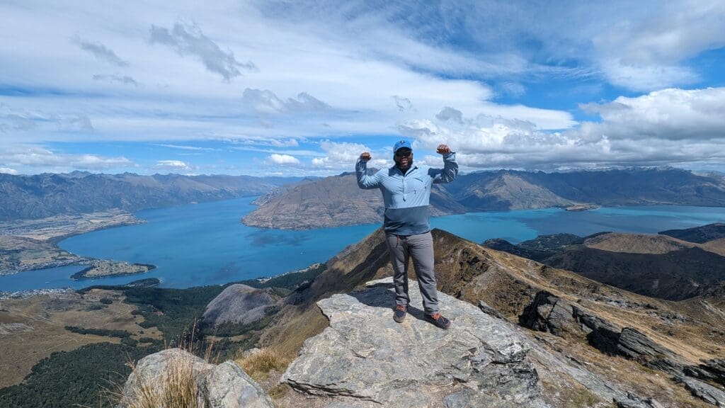 a man standing on a rock with arms raised on top of a mountain