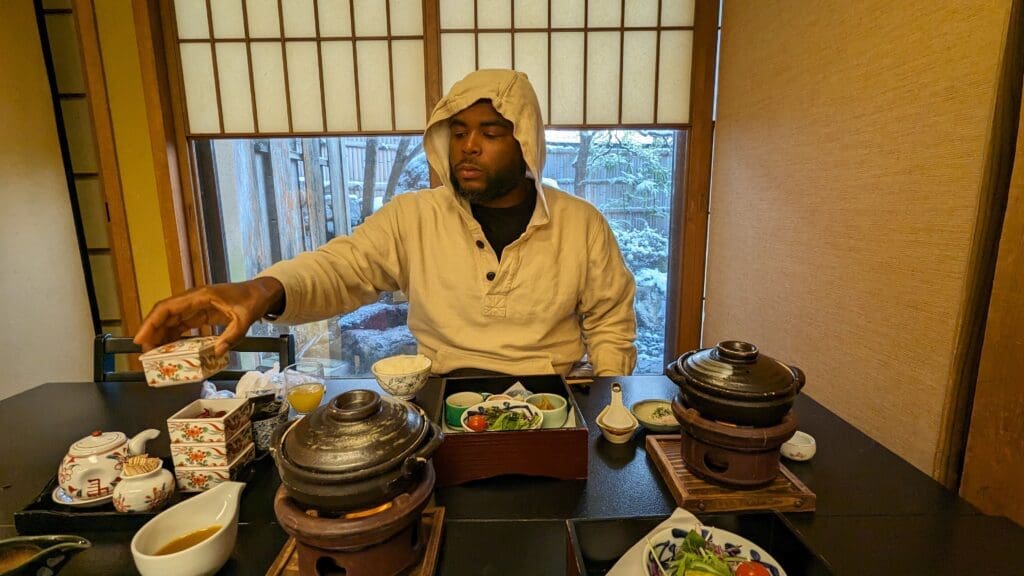 a man in a hoodie sitting at a table with food