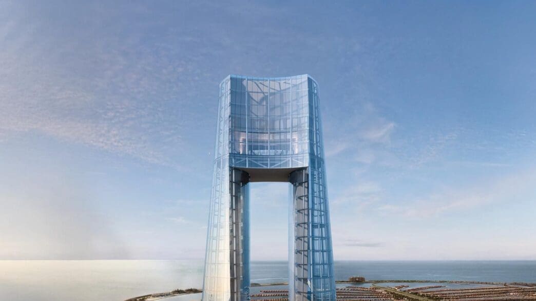 a glass tower with a body of water and a city in the background