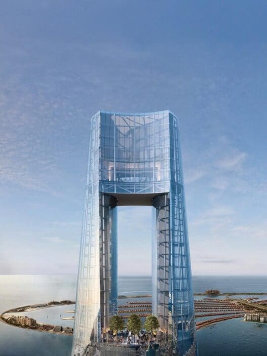 a glass tower with a body of water and a city in the background