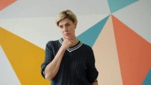 a woman with short blonde hair wearing a black sweater with a white collar